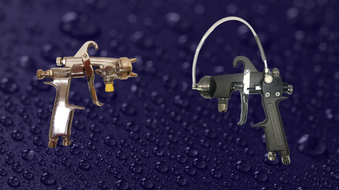 Two water-based spray guns displayed on a textured surface with droplets of water.
